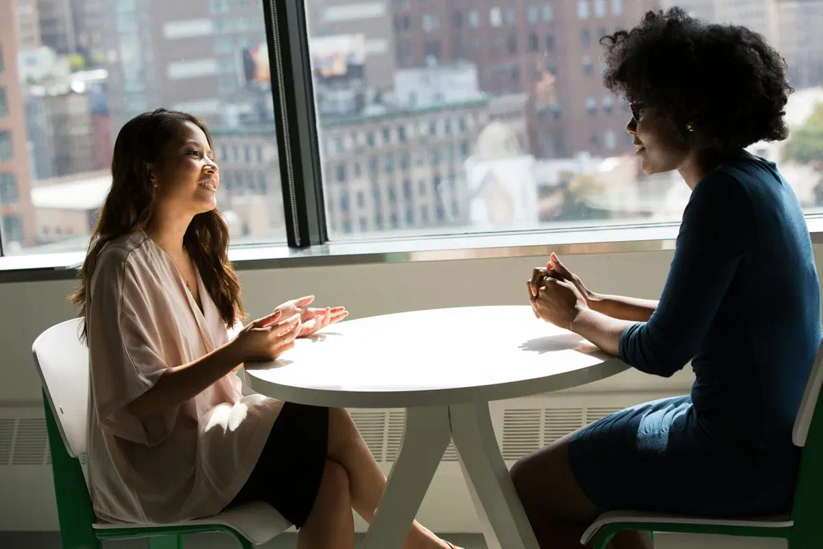 Two women talking across a table during a financial consultation