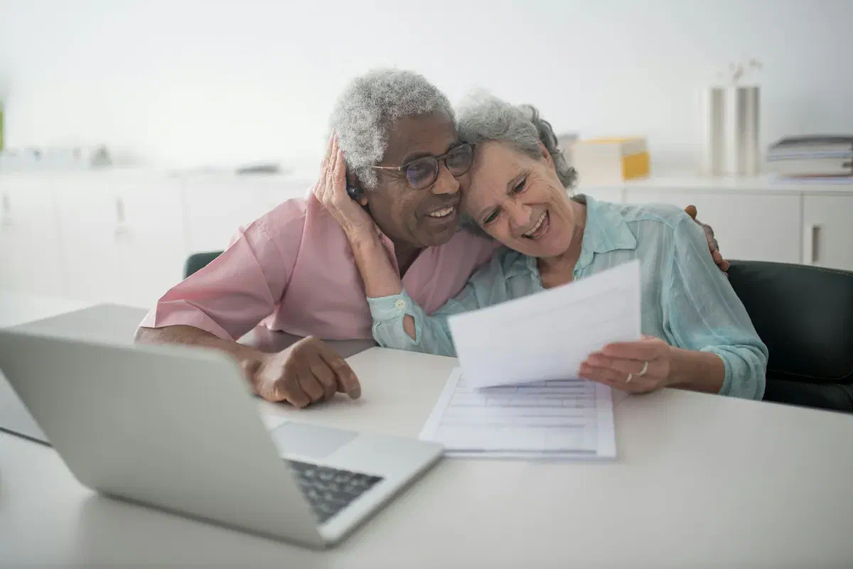 A smiling older couple reviewing their finances together
