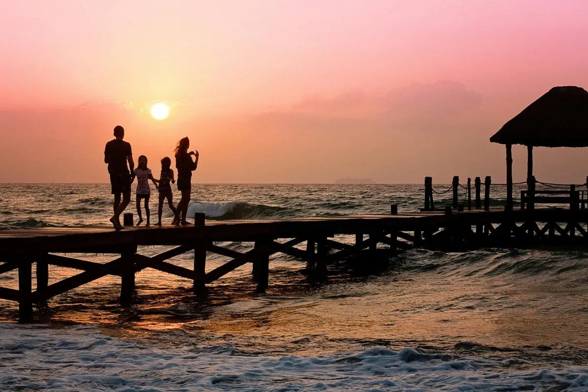 A family standing together on a pier at sunset