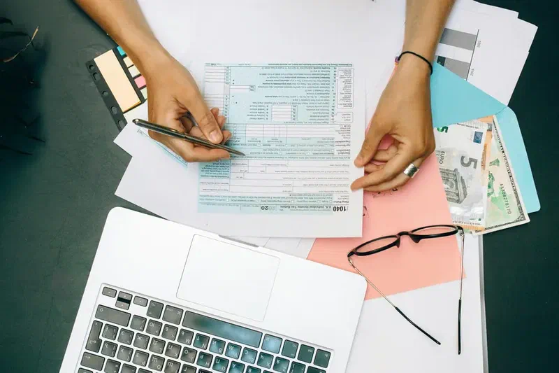 Hands reviewing financial paperwork next to a laptop